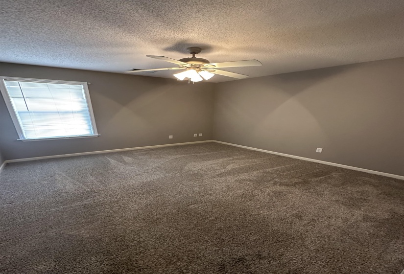 Spare room with dark colored carpet, a textured ceiling, and a ceiling fan