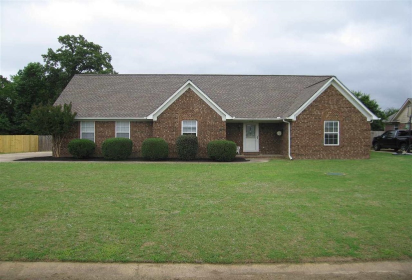 Single story home featuring a shingled roof, covered porch, and brick siding