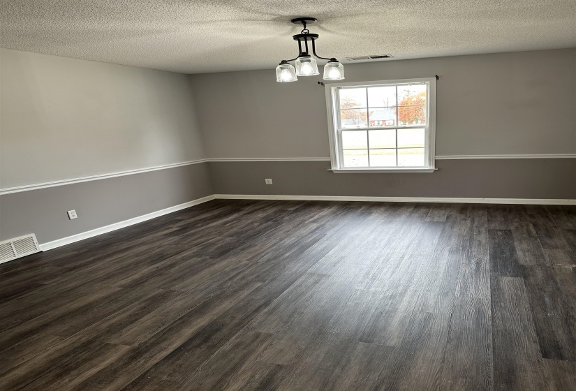 Spare room featuring a textured ceiling, dark wood-style floors, and a chandelier