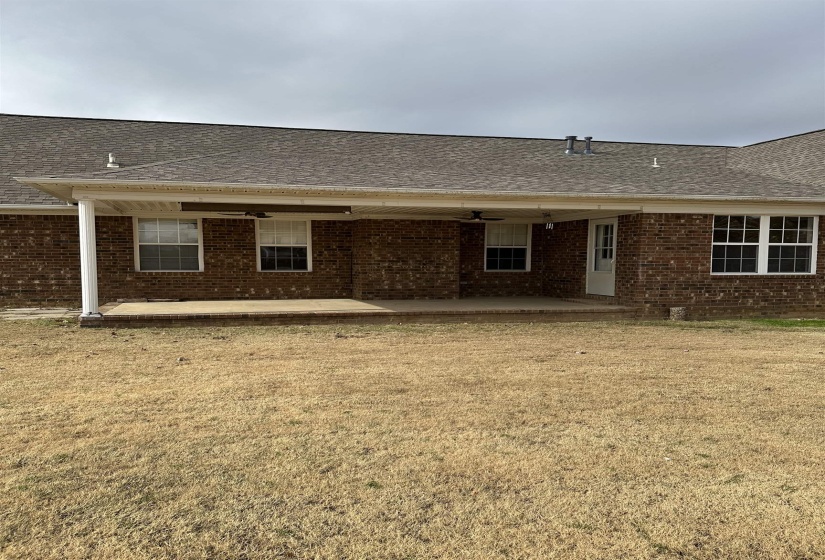 Rear view of house with a patio, a yard, and brick siding