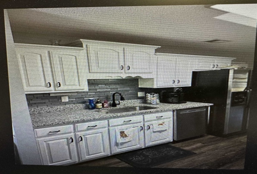 Kitchen featuring tasteful backsplash, light stone counters, white cabinetry, stainless steel appliances, and dark wood-style flooring