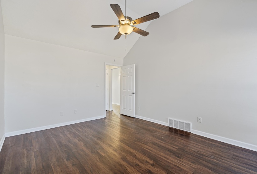 Empty room with high vaulted ceiling, dark wood-style floors, and ceiling fan