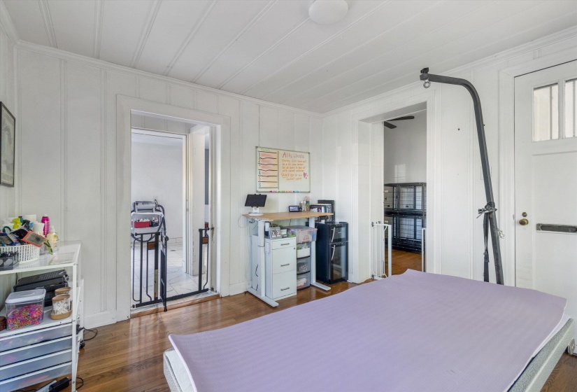 Bedroom with dark wood-style floors, ornamental molding, and a decorative wall