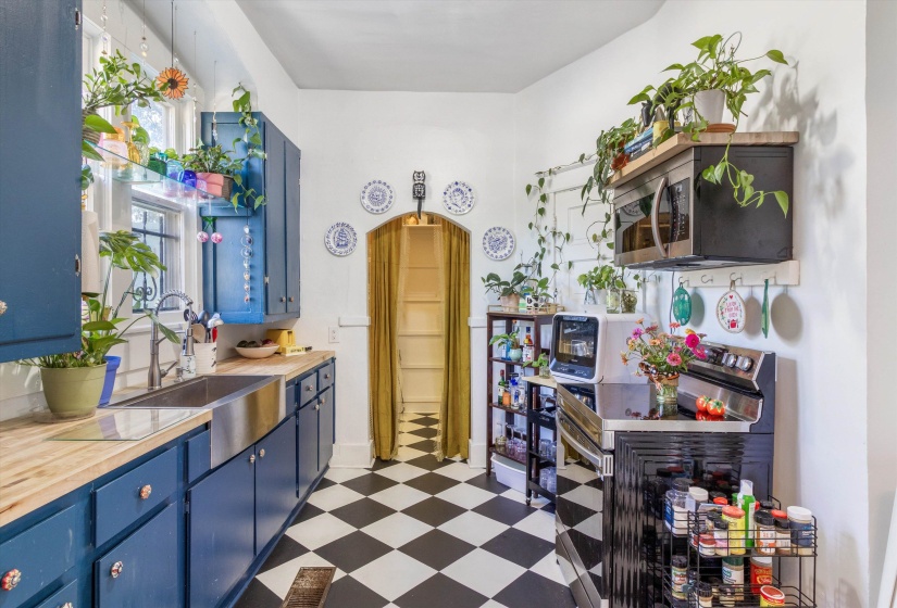 Kitchen featuring blue cabinetry, stainless steel appliances, dark floors, and wooden counters
