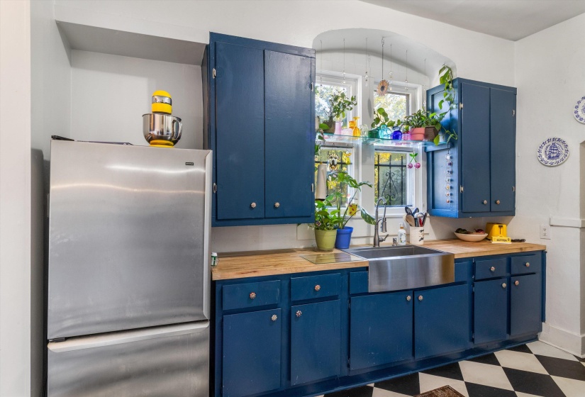 Kitchen with blue cabinets, freestanding refrigerator, light flooring, and wood counters