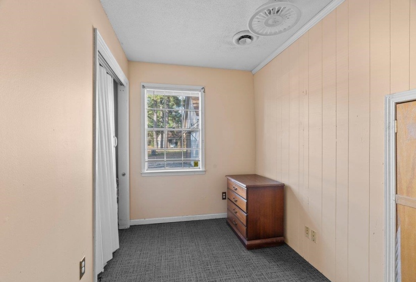 Unfurnished bedroom with dark colored carpet, a textured ceiling, and wood walls