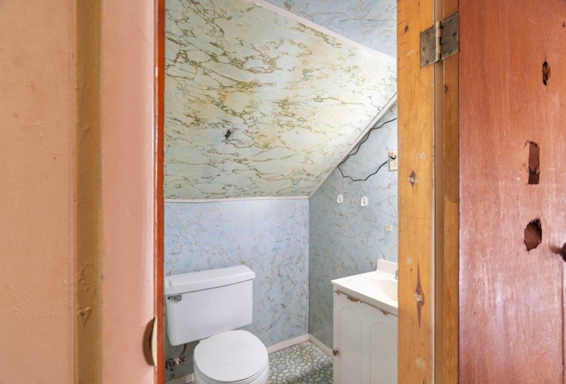 Bathroom featuring lofted ceiling, wallpapered walls, and vanity