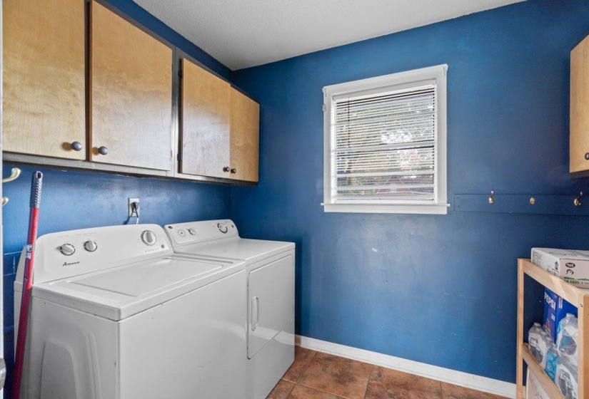 Laundry area featuring cabinet space, washing machine and clothes dryer, and dark tile patterned floors