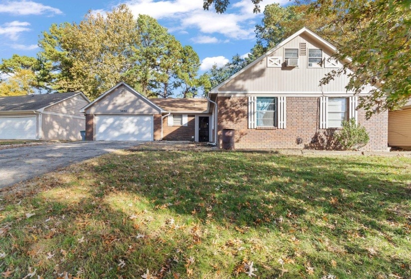 View of front of home featuring brick siding, a front yard, driveway, and a garage