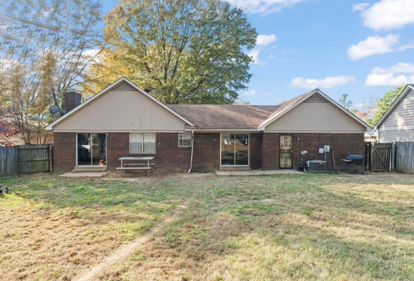 Back of property with a fenced backyard, brick siding, a chimney, and a gate