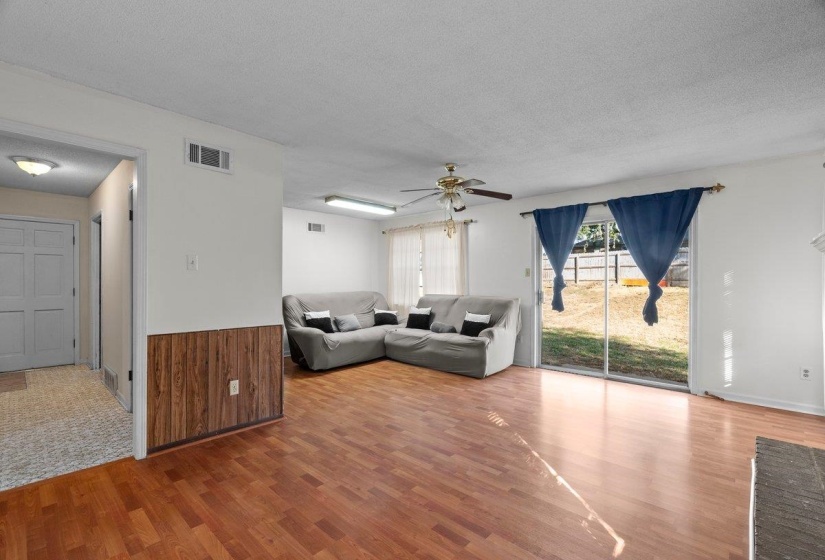 Living room with a textured ceiling, wood finished floors, a wainscoted wall, ceiling fan, and wooden walls