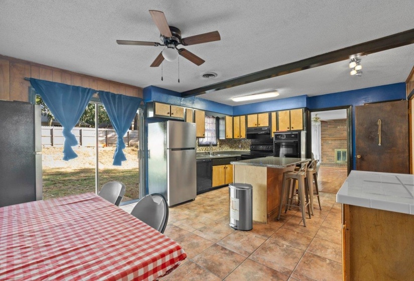 Kitchen featuring black appliances, a textured ceiling, healthy amount of natural light, beamed ceiling, and a center island