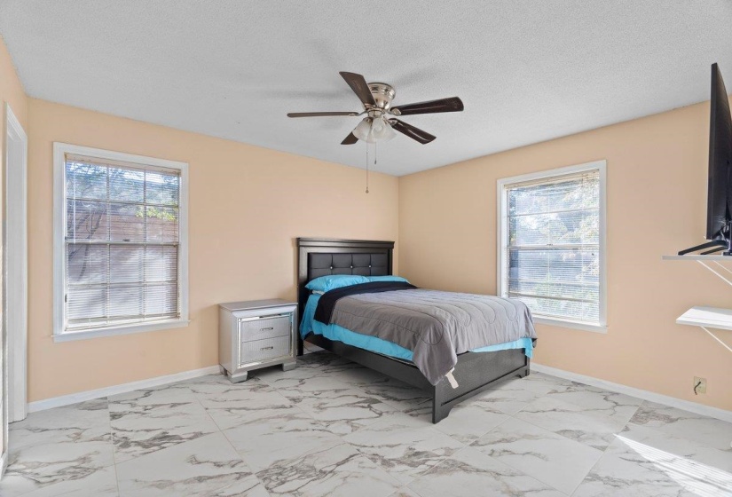 Bedroom featuring light marble finish flooring, a textured ceiling, and ceiling fan