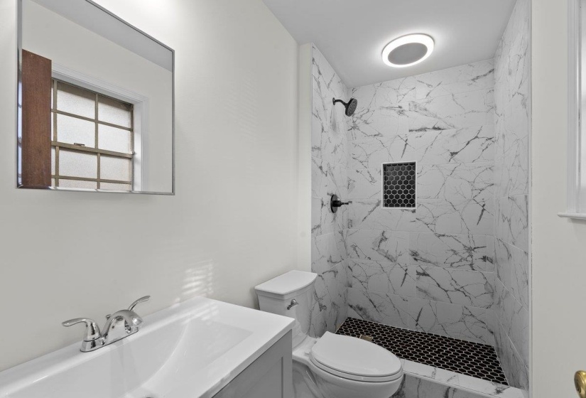 Full bath featuring vanity and a marble finish shower