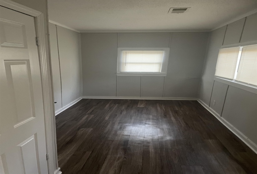 Unfurnished room featuring dark wood-style floors, a decorative wall, a textured ceiling, and crown molding