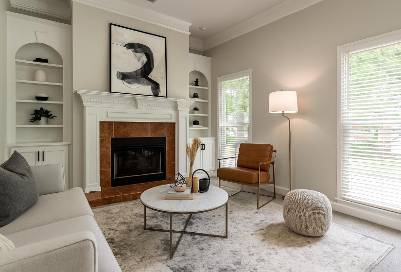 Living room featuring built in features, ornamental molding, and a fireplace