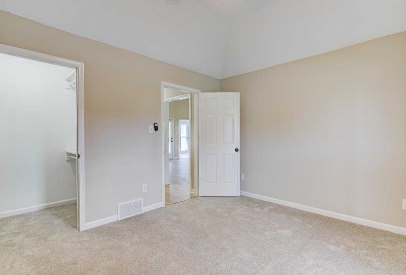 Unfurnished bedroom with carpet, a walk in closet, and baseboards