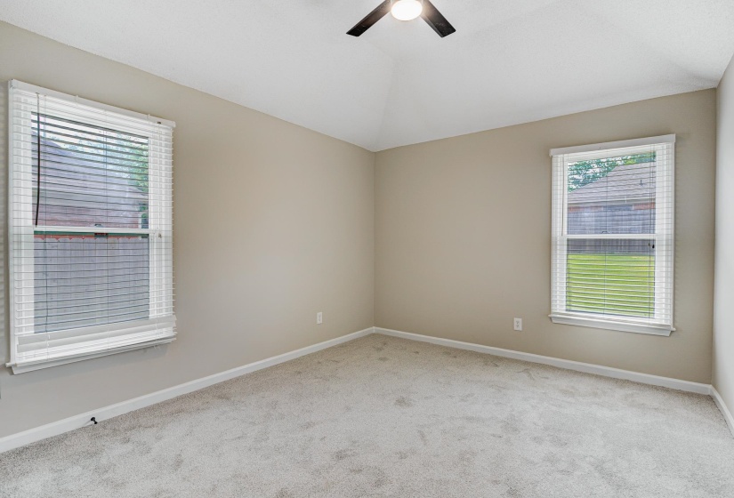 Carpeted spare room with ceiling fan, baseboards, and vaulted ceiling