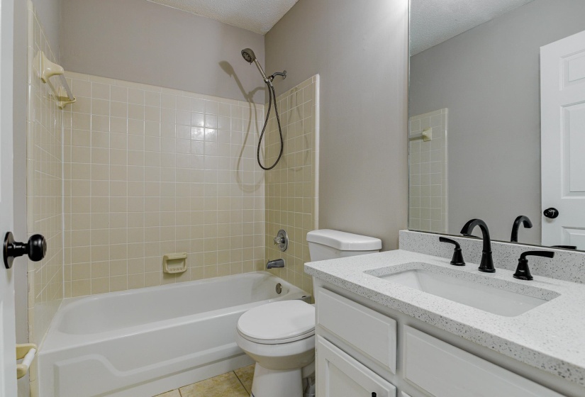 Bathroom featuring vanity, tile patterned flooring, shower / bath combination, toilet, and a textured ceiling