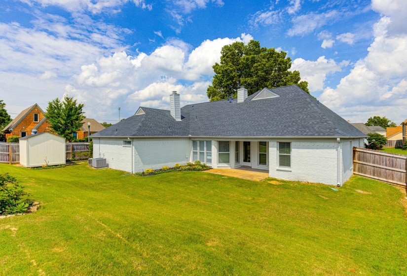 Back of property with brick siding, a chimney, central AC unit, a shingled roof, and a patio area