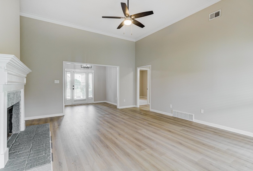 Unfurnished living room with a towering ceiling, a ceiling fan, a chandelier, ornamental molding, and a fireplace with raised hearth