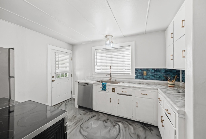 Kitchen featuring light countertops, stainless steel appliances, white cabinets, tasteful backsplash, and dark marble finish floors