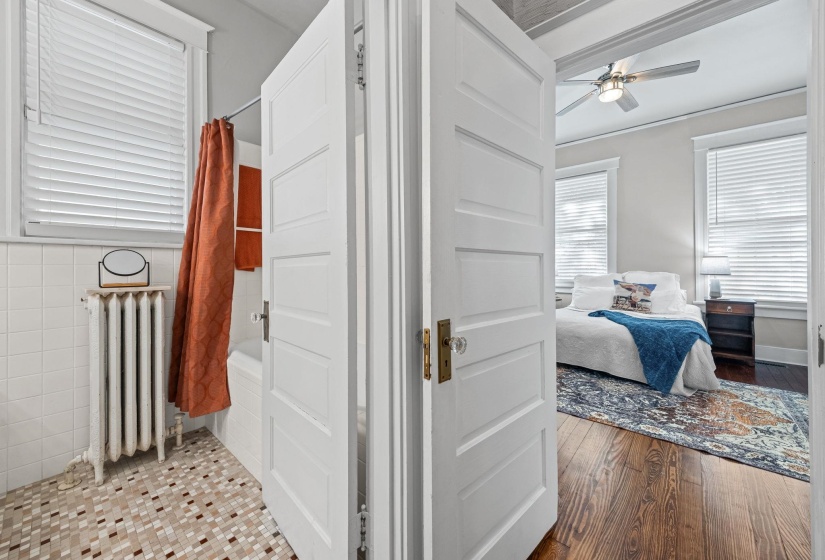 Ensuite bathroom featuring shower / bath combo with shower curtain, radiator heating unit, dark wood-style flooring, and ceiling fan