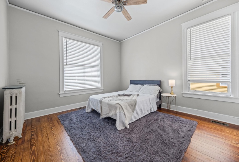 Bedroom featuring radiator heating unit, hardwood / wood-style flooring, a ceiling fan, and ornamental molding