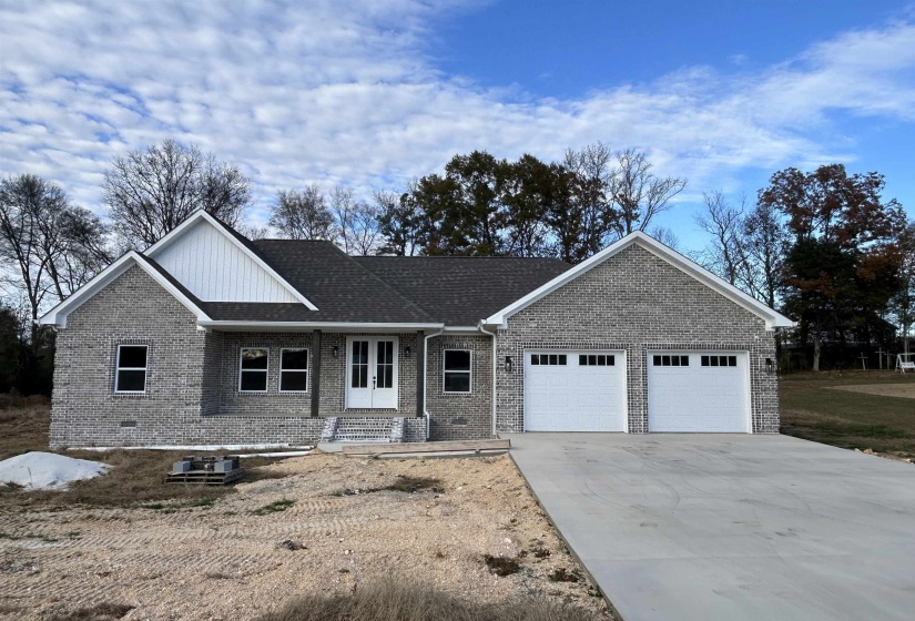 Single story home with covered porch, brick siding, driveway, and an attached 2 car garage.