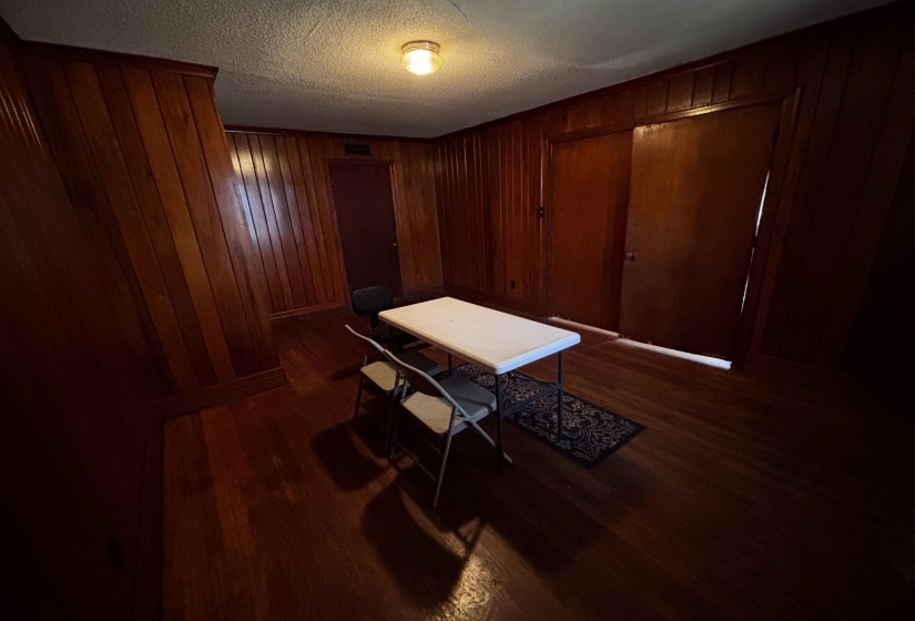 Office space with a textured ceiling, wooden walls, and dark wood-style flooring