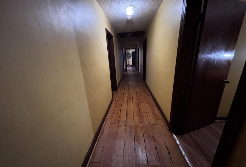 Hall featuring a textured ceiling and dark wood finished floors