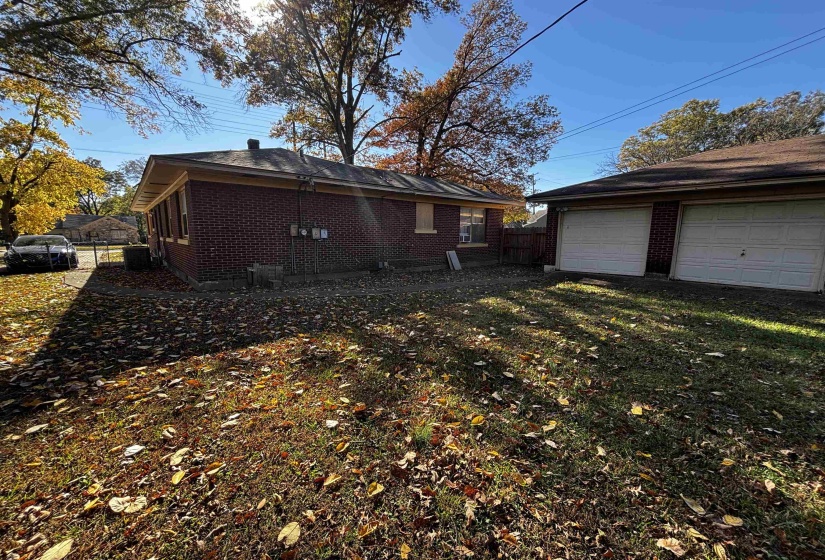 View of home's exterior featuring brick siding, a detached garage, and an outbuilding