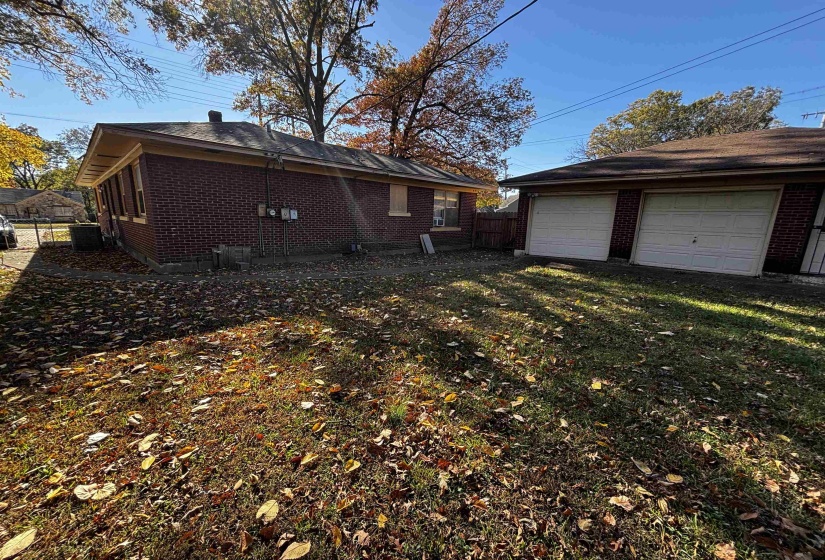 View of property exterior with brick siding, a garage, and an outbuilding