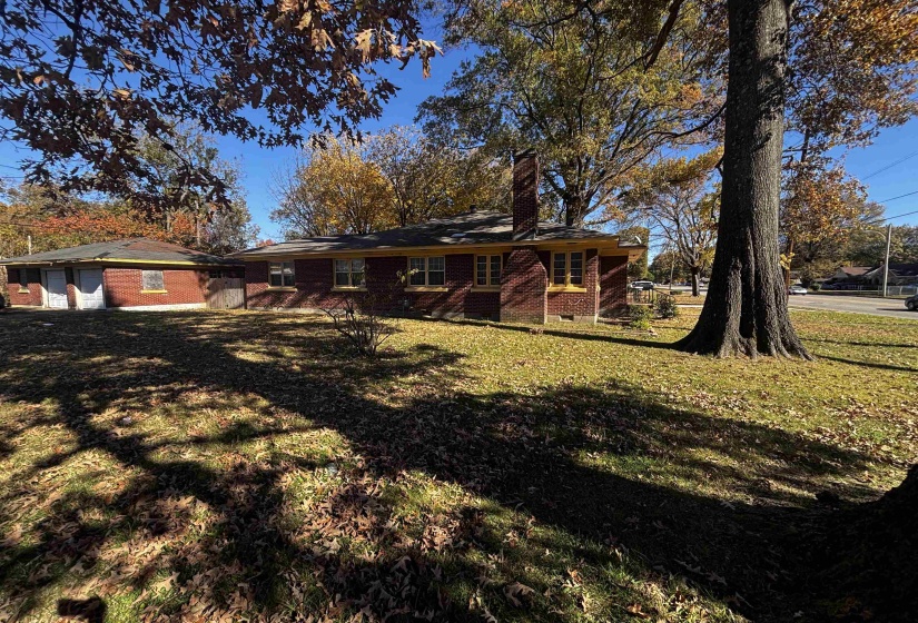 Rear view of house featuring brick siding, a yard, and a chimney