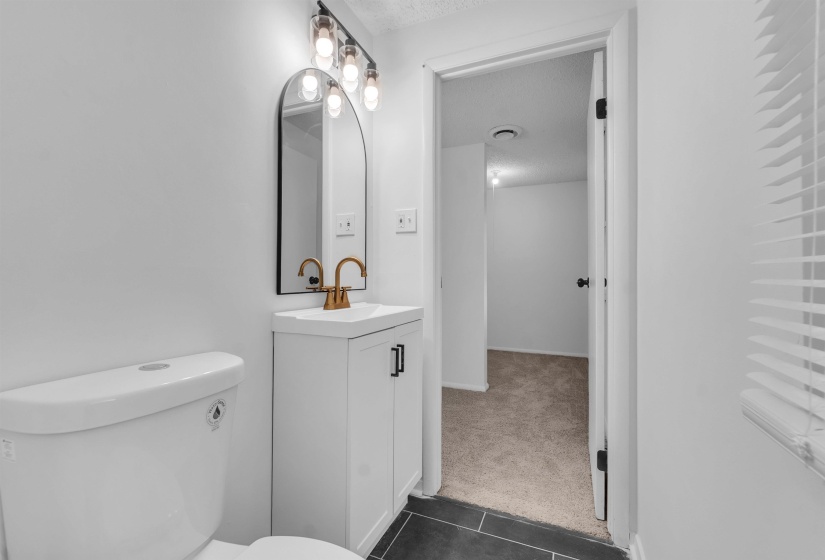 Bathroom featuring dark colored carpet, vanity, dark tile patterned floors, and a textured ceiling