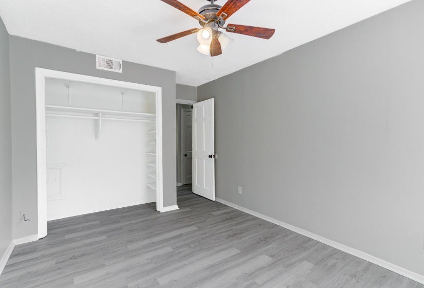 Unfurnished bedroom featuring wood finished floors, a closet, and a ceiling fan