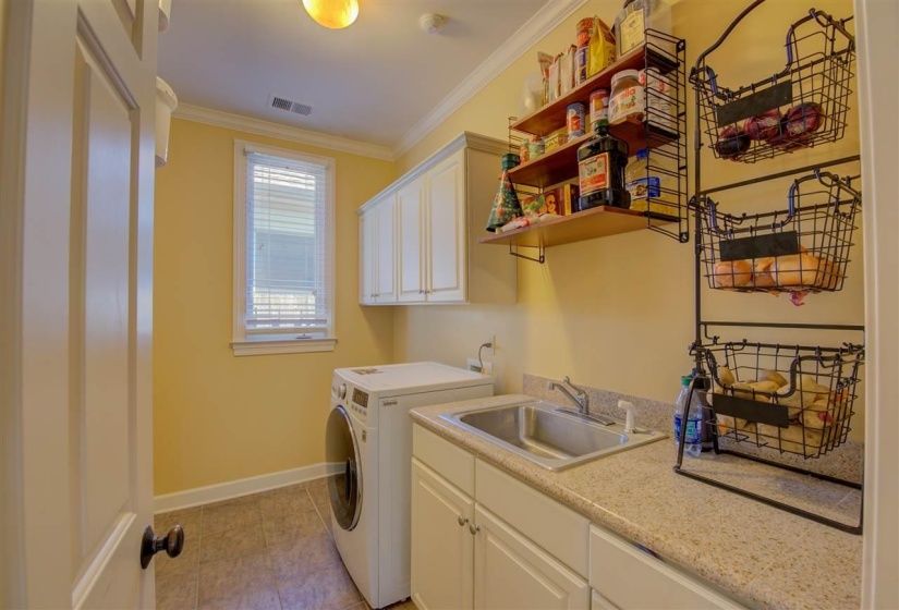 Laundry room featuring crown molding, cabinet space, washer and dryer, and light tile patterned floors