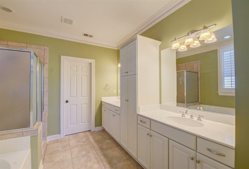 Full bathroom with crown molding, two vanities, light tile patterned floors, a tub to relax in, and a shower stall