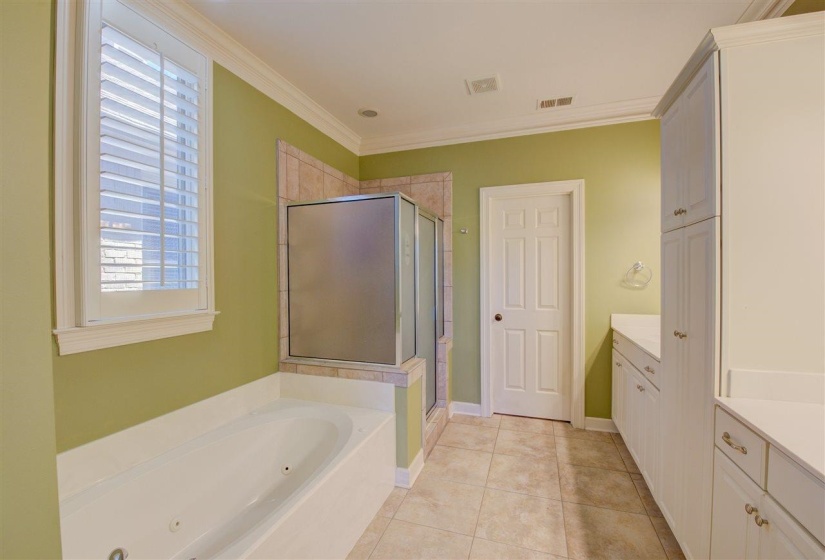 Full bathroom featuring vanity, light tile patterned flooring, a jetted tub, a stall shower, and ornamental molding
