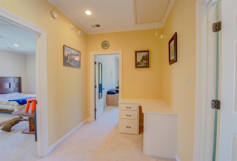 Hall featuring light carpet, ornamental molding, attic access, recessed lighting, and a desk