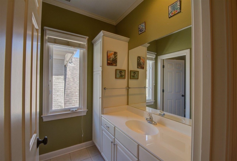 Half bathroom with vanity, ornamental molding, and light tile patterned floors