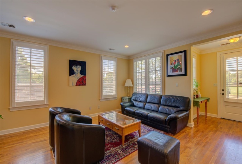 Living room with ornamental molding, light wood-style flooring, and recessed lighting