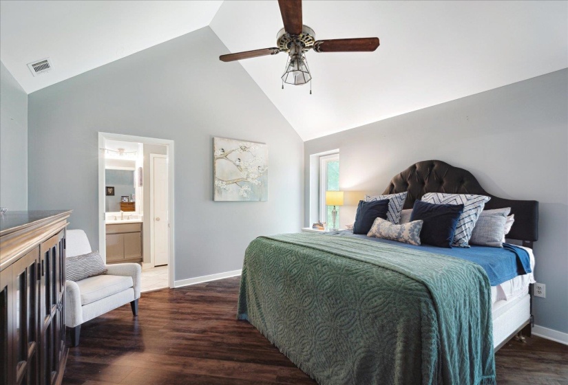Bedroom with wood finished floors, high vaulted ceiling, baseboards, ceiling fan, and ensuite bathroom