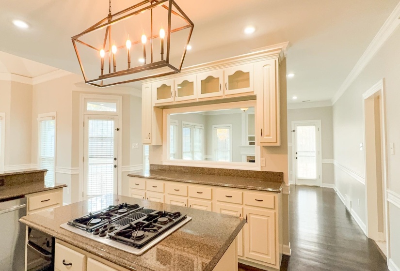 Kitchen with healthy amount of natural light, a kitchen island, ornamental molding, recessed lighting, and dark stone countertops