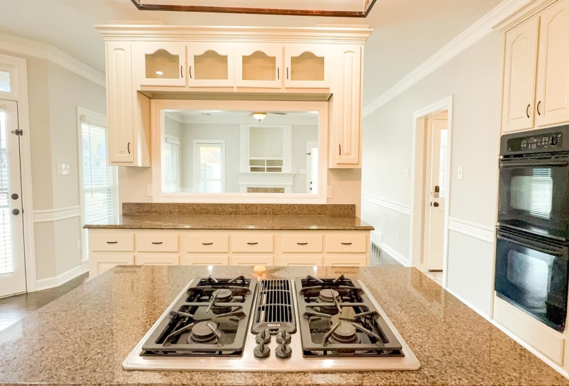 Kitchen featuring stainless steel gas stovetop, crown molding, and light stone counters