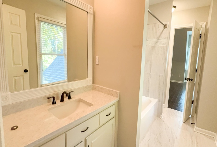 Full bath featuring vanity, shower / tub combo, and light marble finish floors
