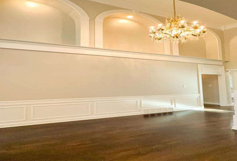 Unfurnished dining area with a decorative wall, a chandelier, a high ceiling, and a wainscoted wall