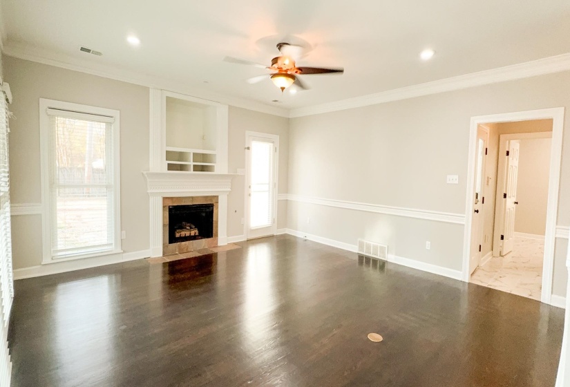 Unfurnished living room with ceiling fan, crown molding, a fireplace, wood finished floors, and recessed lighting