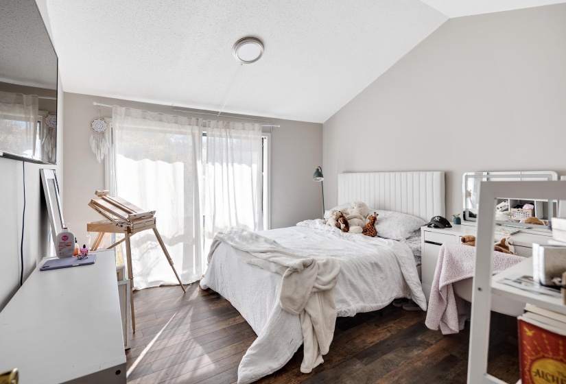Bedroom featuring dark wood-style flooring, vaulted ceiling, and a textured ceiling