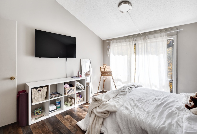 Bedroom with vaulted ceiling, a textured ceiling, and wood finished floors